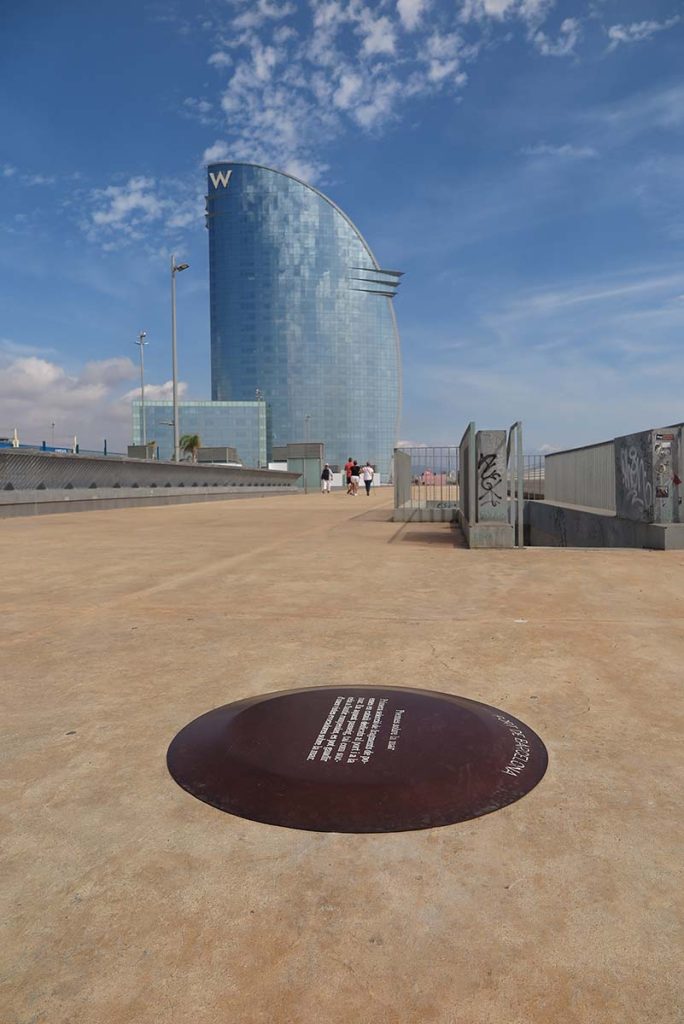 Tope in acciaio corten sul pavimento, accanto all'hotel Vela a Barcellona.